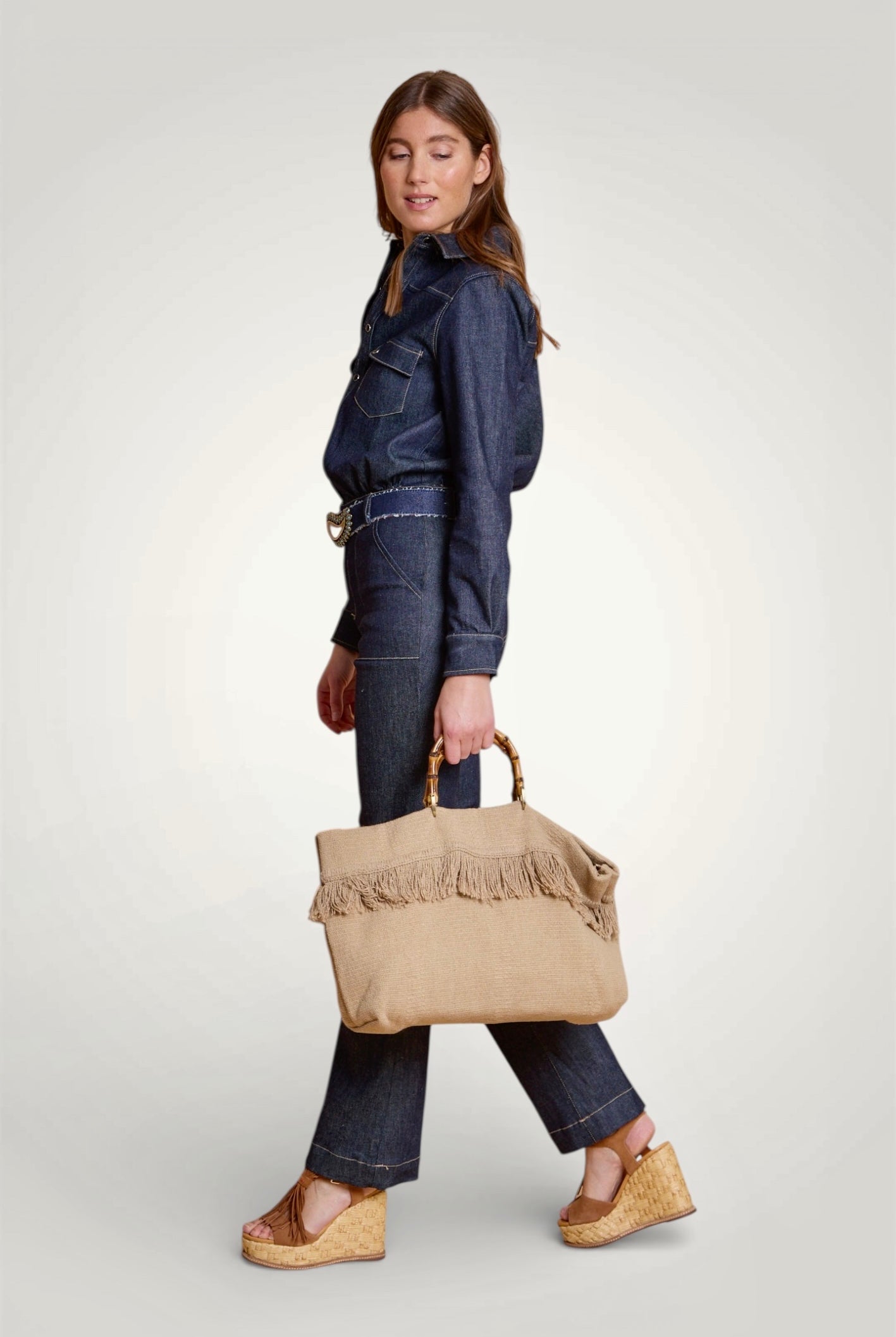 Silouhette de la combinaison en denim bleu brut avec taille marquée et jambes évasées. Vue de profil.