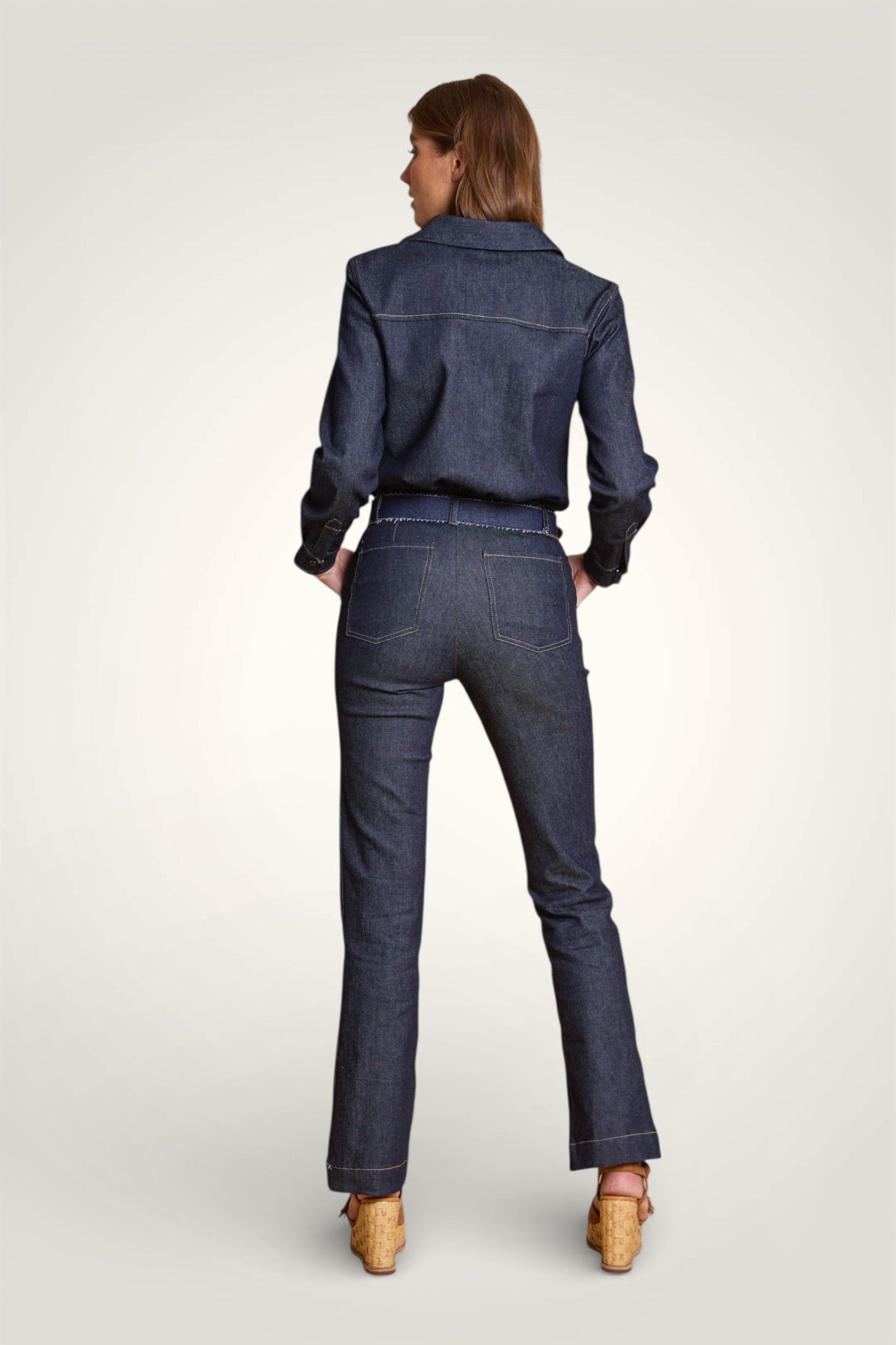 Dos de la combinaison en denim bleu brut avec taille marquée et jambes évasées.