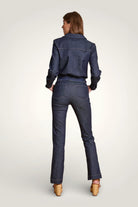 Dos de la combinaison en denim bleu brut avec taille marquée et jambes évasées.