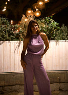 Combinaison de cérémonie en lurex plissé rose parme avec coupe américaine portée de face.