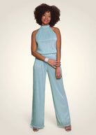 Combinaison de cérémonie en lurex plissé vert aqua avec coupe américaine portée de face.
