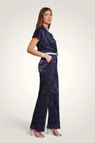 Vue de profil de la combinaison pantalon fluide avec jambes larges d'inspiration disco. Coloris bleu marine.