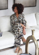 Ensemble fluide chemise et pantalon large motif léopard pour femme vue assise dans un canapé.