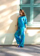 Ensemble en satin fluide avec haut asymétrique et pantalon large imprimé tropical.
